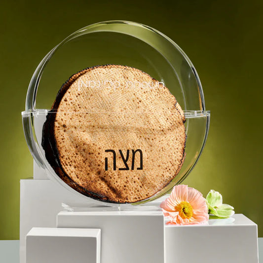 Round standing matzah box on a white platform with flowers, against a green background - AFH Bargains